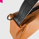 Detail des schwarzen Leder-Schulterriemens mit Metallring an der Cromia Alyson Beuteltasche in Cognac
